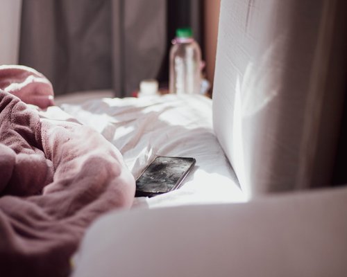 Phone placed aside near a bed in a calm evening scene