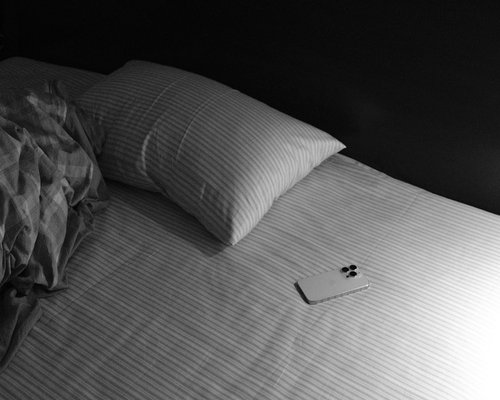 Phone placed aside near a bed in a calm evening scene